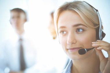 Kulaklıklı, güler yüzlü iş kadını müşterilere danışıyor. Sunny Office 'de çalışan çeşitli telefon operatörleri. Çağrı merkezi ve iş adamları kavramı.