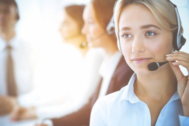 Kulaklıklı, güler yüzlü iş kadını müşterilere danışıyor. Sunny Office 'de çalışan çeşitli telefon operatörleri. Çağrı merkezi ve iş adamları kavramı.