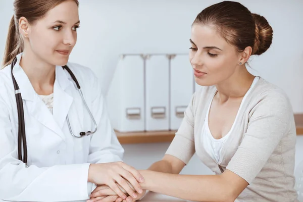 El médico y el paciente están sentados y discutiendo los resultados del examen de salud en el consultorio clínico. Salud, medicina y conceptos de buenas noticias — Foto de Stock