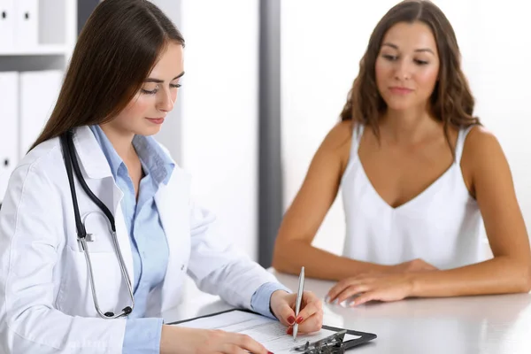 Doutor e paciente feliz conversando enquanto sentado na mesa. O médico ou terapeuta discutindo o estilo de vida saudável. Conceito de cuidados de saúde, medicina e serviço ao paciente — Fotografia de Stock