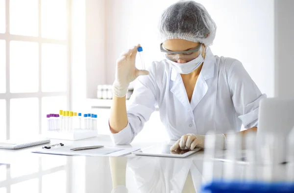 Cientista profissional em óculos de proteção pesquisando tubo com reagentes em laboratório ensolarado. Medicina e pesquisa — Fotografia de Stock