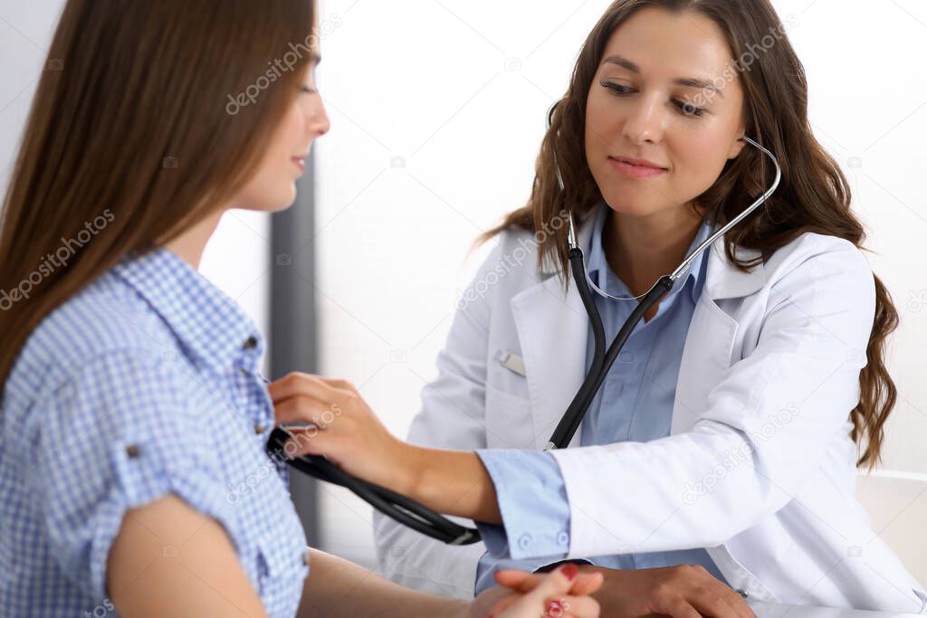 Doctor with a stethoscope in the hand examining her female patient. Health care, cardiology and medicine concepts