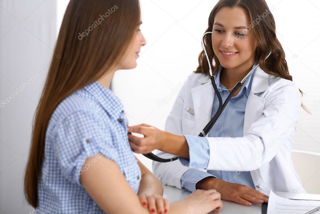 Doctor with a stethoscope in the hand examining her female patient. Health care, cardiology and medicine concepts