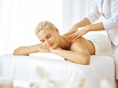 Güzel sarışın kadın kapalı gözlerle sırt masajından hoşlanıyor. Spa salonu konsepti
