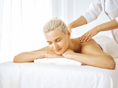 Güzel sarışın kadın kapalı gözlerle sırt masajından hoşlanıyor. Spa salonu konsepti