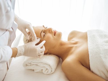 Güzellik uzmanı elleri şırıngayla kadın yüzüne güzellik prosedürü uyguluyor. Kozmetik tıp ve cerrahi, güzellik enjeksiyonları konsepti