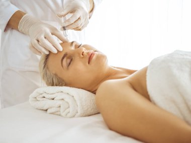 Güzellik uzmanı elleri şırıngayla kadın yüzüne güzellik prosedürü uyguluyor. Kozmetik tıp ve cerrahi, güzellik enjeksiyonları konsepti