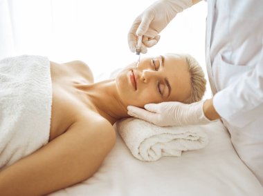 Güzellik uzmanı elleri şırıngayla kadın yüzüne güzellik prosedürü uyguluyor. Kozmetik tıp ve cerrahi, güzellik enjeksiyonları konsepti