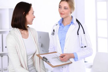 Hastane muayenehanesindeki genç kadın doktor ve hasta. Terapistin mavi renkli bluzu iyi görünüyor. Tıp ve sağlık hizmetleri kavramı