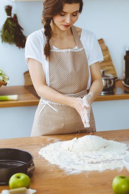 Genç esmer kadın mutfakta pizza ya da el yapımı makarna pişiriyor. Ev hanımı ahşap masada hamur hazırlıyor. Diyet, gıda ve sağlık konsepti