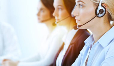 Güneşli ofiste çalışan bir grup farklı telefon operatörü. Kulaklıklı yakışıklı iş kadını müşterilere danışıyor. Çağrı merkezi ve iş adamları kavramı