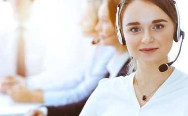 Güneşli ofiste çalışan bir grup farklı telefon operatörü. Kulaklıklı yakışıklı iş kadını müşterilere danışıyor. Çağrı merkezi ve iş adamları kavramı