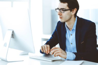 Modern ofiste bilgisayarla çalışan bir iş adamı. İş yerindeki erkek girişimcinin ya da şirket müdürünün vesikalığı. İş konsepti