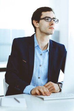 Modern ofiste bilgisayarla çalışan bir iş adamı. İş yerindeki erkek girişimcinin ya da şirket müdürünün vesikalığı. İş konsepti