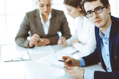 Bir grup iş adamı modern ofiste soruları tartışıyor. Pazarlıktaki iş adamının vesikalığı. Takım çalışması, ortaklık ve iş konsepti