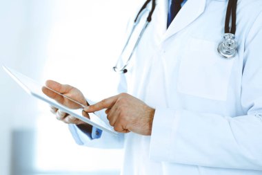 Doktor, ağ araştırması ya da sanal hastalık tedavisi için tablet bilgisayar kullanıyor. Eller yakın çekim. Klinikte mükemmel bir tıbbi hizmet. Modern tıp, tıbbi veri ve sağlık hizmetleri kavramları. Ayarlanmış