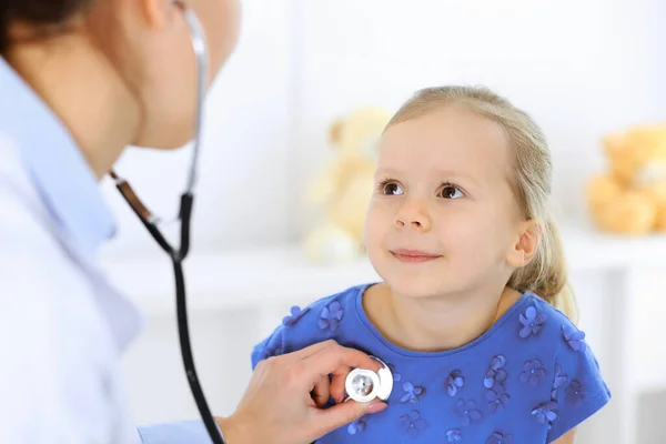 Doutor examinando uma menina por estetoscópio. Paciente de criança sorridente feliz em inspeção médica habitual. Conceitos de medicina e saúde — Fotografia de Stock