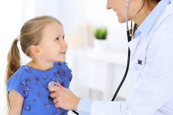 Doctor examinando a una niña por estetoscopio. Feliz niño sonriente paciente en la inspección médica habitual. Medicina y conceptos sanitarios —  Fotos de Stock