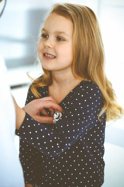 Médico examinando a un niño paciente por estetoscopio. Linda niña en la cita con el médico. Concepto de medicina. Foto tonificada — Foto de Stock