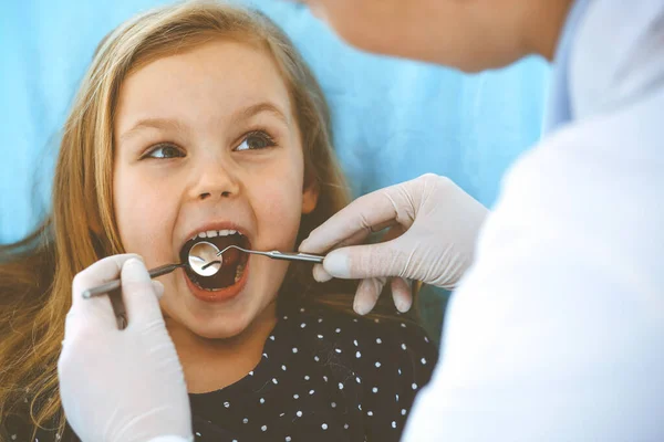 Menina sentada na cadeira dentária com a boca aberta durante o check-up oral, enquanto médico. Consulta ao dentista. Conceito de medicina. Foto tonificada — Fotografia de Stock