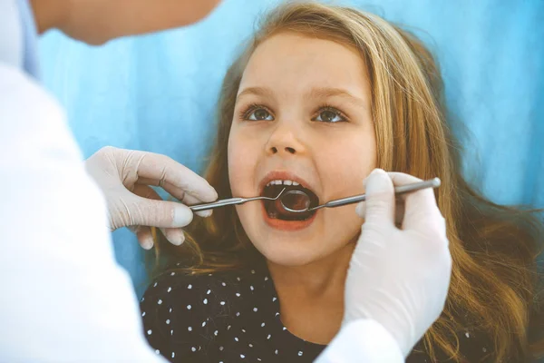 Mała dziewczynka siedzi na krześle dentystycznym z otwartymi ustami podczas kontroli doustnej, podczas gdy lekarz. Odwiedzam gabinet dentystyczny. Koncepcja medyczna. Uszkodzone zdjęcie — Zdjęcie stockowe