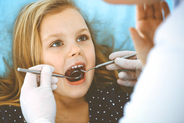 Little baby girl sitting at dental chair with open mouth during oral check up while doctor. Visiting dentist office. Medicine concept. Toned photo