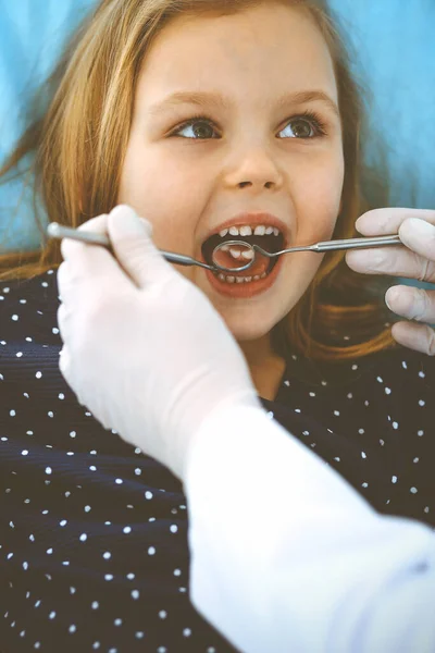 Mała dziewczynka siedzi na krześle dentystycznym z otwartymi ustami podczas kontroli doustnej, podczas gdy lekarz. Odwiedzam gabinet dentystyczny. Koncepcja medyczna. Uszkodzone zdjęcie — Zdjęcie stockowe