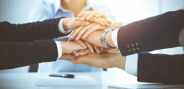 Business team toont eenheid met hun handen bij elkaar in het zonnige kantoor. Groep mensen die de handen ineenslaan en het concept van vriendschap, teamwork en partnerschap vertegenwoordigen — Stockfoto