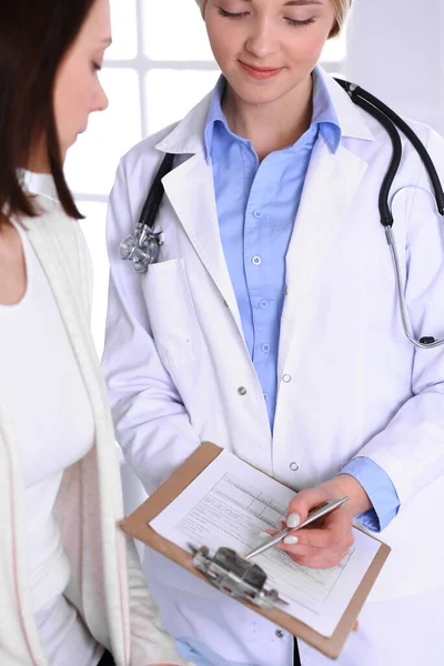 Hastane muayenehanesindeki genç kadın doktor ve hasta. Terapistin mavi renkli bluzu iyi görünüyor. Tıp ve sağlık hizmetleri kavramı — Stok fotoğraf