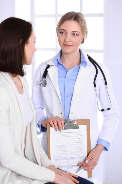 Hastane muayenehanesindeki genç kadın doktor ve hasta. Terapistin mavi renkli bluzu iyi görünüyor. Tıp ve sağlık hizmetleri kavramı — Stok fotoğraf
