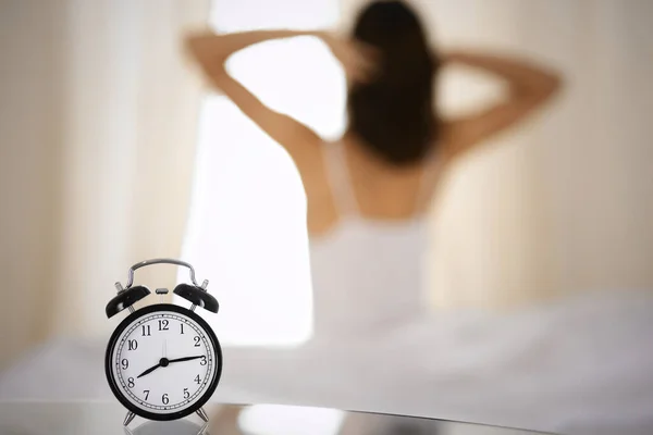 Femme étirant les mains au lit après le réveil, éruption de soleil. Brunette entrant dans une journée heureuse et détendue après une bonne nuit de sommeil et vue arrière. Concept d'une nouvelle journée et d'un week-end joyeux — Photo