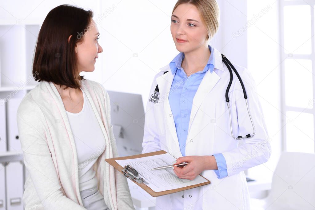 Young woman doctor and patient at medical examination at hospital office. Blue color blouse of therapist looks good. Medicine and healthcare concept