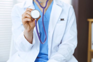 Bilinmeyen doktor kadın steteskop başı tutuyor, yakın plan. Doktor hastayı muayene etmeye ve yardım etmeye hazır. Sağlık hizmetleri, en iyi tedavi ve tıp konseptinde yardım ve sigorta