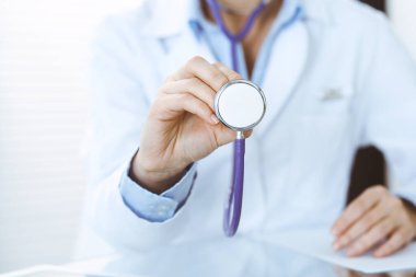 Bilinmeyen doktor kadın steteskop başı tutuyor, yakın plan. Doktor hastayı muayene etmeye ve yardım etmeye hazır. Sağlık hizmetleri, en iyi tedavi ve tıp konseptinde yardım ve sigorta