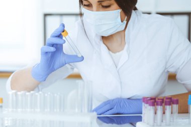 Koruyucu gözlüklü profesyonel kadın bilim adamının laboratuarda reaktörlerle deney yapması. Tıp ve araştırma konsepti