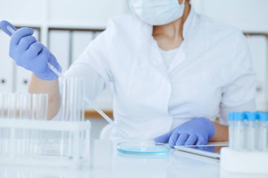 Koruyucu gözlüklü profesyonel kadın bilim adamının laboratuarda reaktörlerle deney yapması. Tıp ve araştırma konsepti