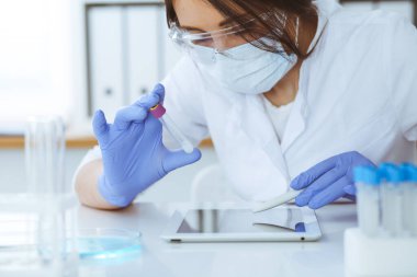 Koruyucu gözlüklü profesyonel kadın bilim adamının laboratuarda reaktörlerle deney yapması. Tıp ve araştırma konsepti