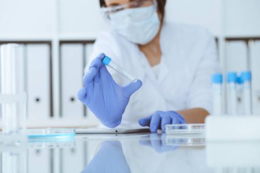 Koruyucu gözlüklü profesyonel kadın bilim adamının laboratuarda reaktörlerle deney yapması. Tıp ve araştırma konsepti