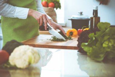Mutfakta pişen bilinmeyen insan elleri. Kadın sebze salatasıyla meşgul. Sağlıklı yemek ve vejetaryen gıda konsepti.