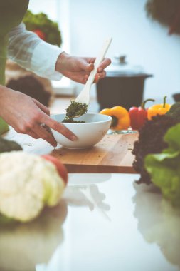Mutfakta pişen bilinmeyen insan elleri. Kadın sebze salatasıyla meşgul. Sağlıklı yemek ve vejetaryen gıda konsepti.