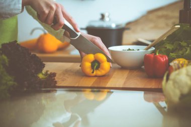 Mutfakta pişen bilinmeyen insan elleri. Sarı dolma biber dilimleyen kadın. Sağlıklı yemek ve vejetaryen gıda konsepti.