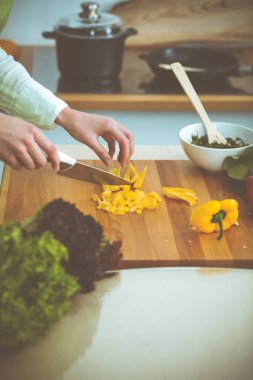 Mutfakta pişen bilinmeyen insan elleri. Sarı dolma biber dilimleyen kadın. Sağlıklı yemek ve vejetaryen gıda konsepti.