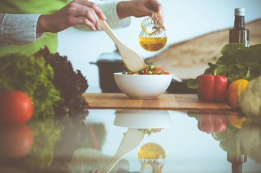 Mutfakta pişen bilinmeyen insan elleri. Kadın sebze salatasıyla meşgul. Sağlıklı yemek ve vejetaryen gıda konsepti.