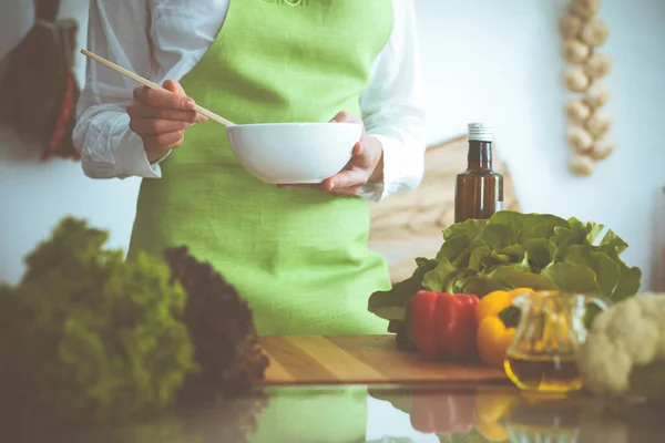 Neznámé lidské ruce vaří v kuchyni. Žena je zaneprázdněná zeleninovým salátem. Zdravé jídlo a koncepce vegetariánských potravin — Stock fotografie