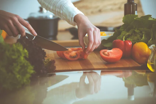 Manos humanas desconocidas cocinando en la cocina. Mujer cortando tomates rojos. Comida saludable y concepto de comida vegetariana —  Fotos de Stock