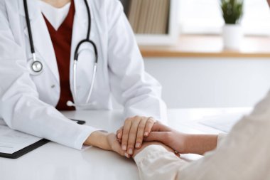 Kadın hastasına güvence veren kimliği belirsiz kadın doktorun elleri, yakın plan. Tıp konsepti.