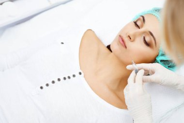 Profesyonel kozmetik uzmanı yüzüne ve dudaklarına iğne yapıyor. Genç bir kadın, yüz hatları ya da büyütme için doldurucu iğneyle doldurulur. Yaşlanma, gençleşme ve hidrasyon prosedürleriyle yüzleş. Estetik kozmetoloji