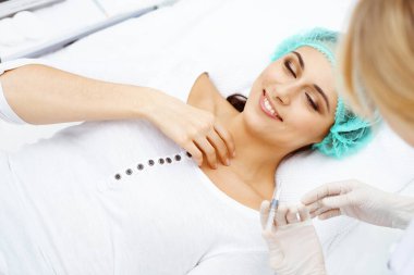 Profesyonel kozmetik uzmanı yüzüne ve dudaklarına iğne yapıyor. Genç bir kadın, yüz hatları ya da büyütme için doldurucu iğneyle doldurulur. Yaşlanma, gençleşme ve hidrasyon prosedürleriyle yüzleş. Estetik kozmetoloji