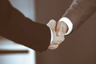 İş adamları toplantıdan ya da pazarlıktan sonra iş arkadaşlarıyla el sıkışıyorlar. Yakın plan. Modern ofisteki bir grup tanınmamış iş adamı ve kadın. Takım çalışması, ortaklık ve tokalaşma konsepti, tonlu resim.