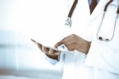 Doktor, ağ araştırması ya da sanal hastalık tedavisi için tablet bilgisayar kullanıyor. Eller yakın çekim. Klinikte mükemmel bir tıbbi hizmet. Modern tıp, tıbbi veri ve sağlık hizmetleri kavramları. Renkli resim.